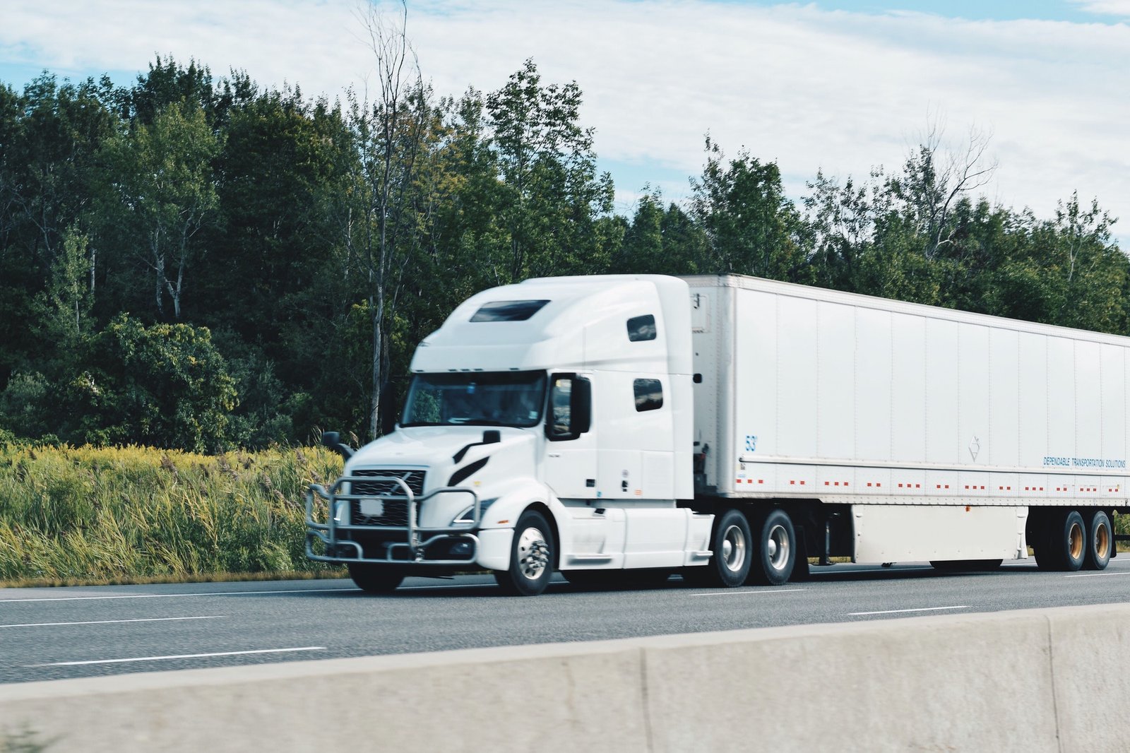 all-white-tractor-trailer-driving-on-a-highway.jpg