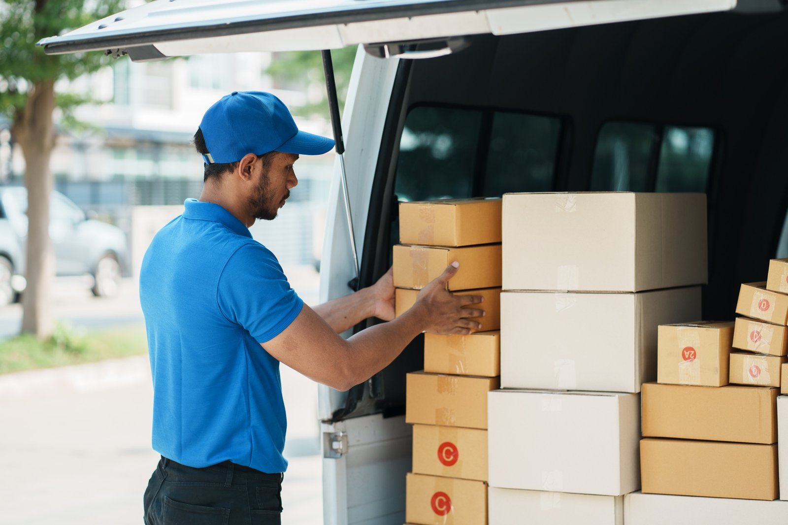 Delivery man organise pile of cardboard boxes in the back of the van. Delivery man organise pile of cardboard boxes in the back of the van.