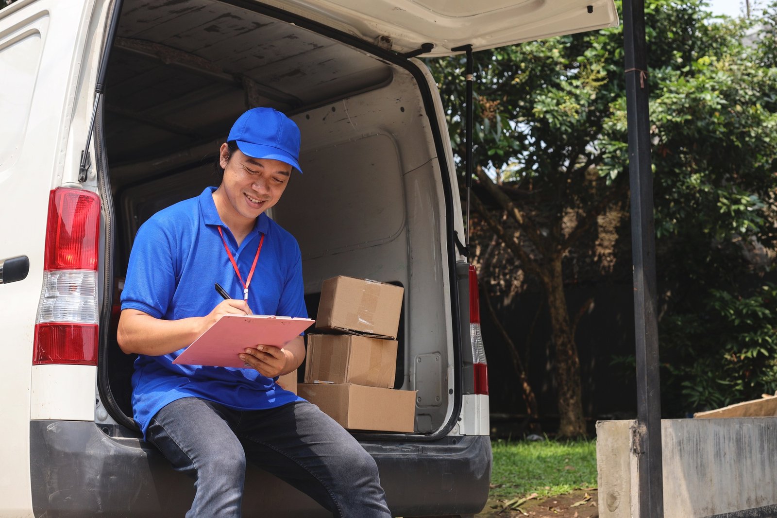 Smiling delivery man writing shipment status Smiling delivery man writing shipment status